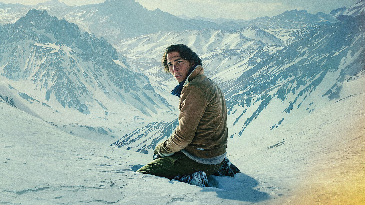 A man on his knees in a snowy mountain landscape.