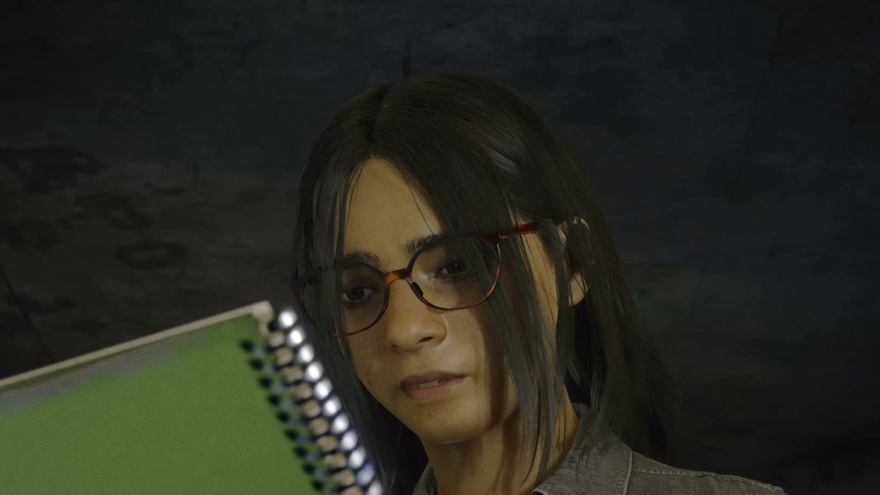 A girl with glasses and brown hair looking at a green notebook.